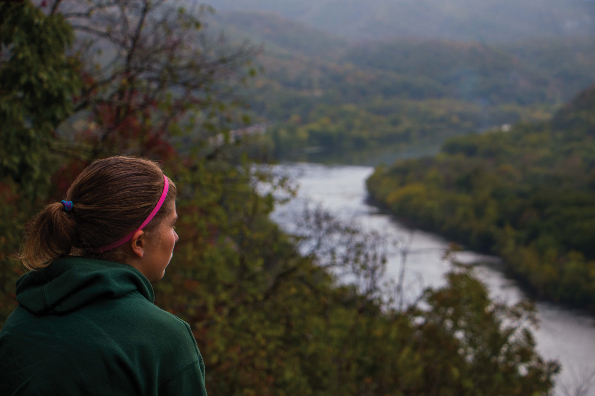 A female student looks out over a vista of forested mountains in West Virginia.