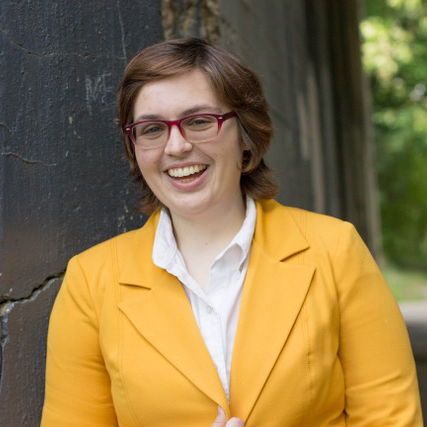 Image of a young woman with short dark hair wearing a bright yellow blazer.