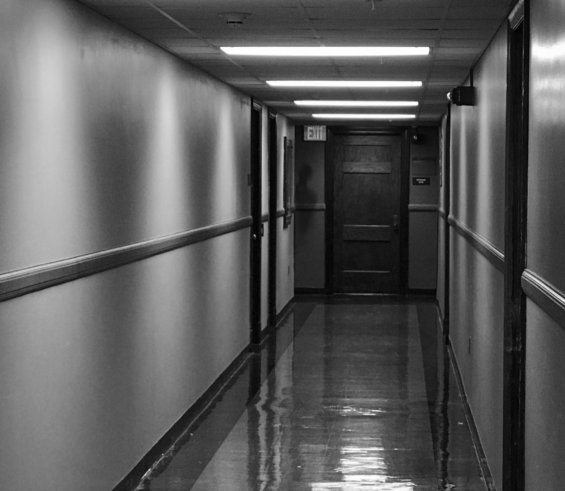 Image shows a hallway in a dorm room. At the end of the hallway is possibly a shadow person. Or photoshop.