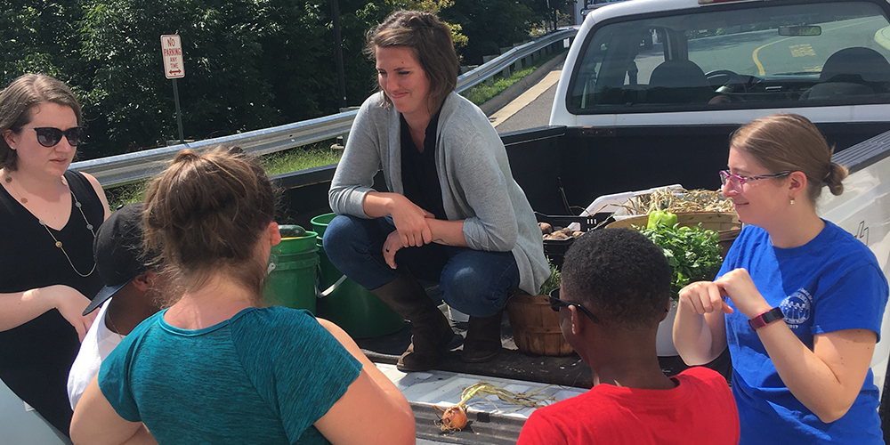 Emily Haas sitting a truck on a farm speaking with several people
