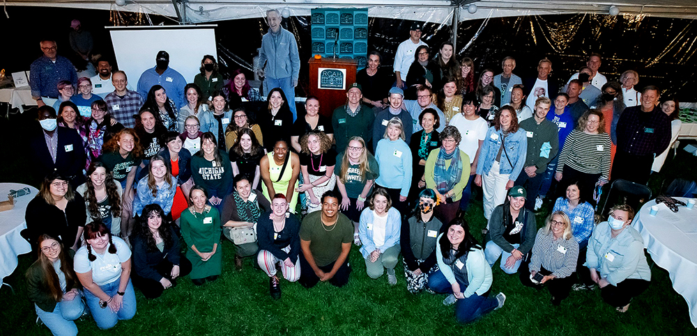 Image is a group photo of alumni, RCAH faculty, RCAH staff, donors, and friends of RCAH celebrating the 2021 Homecoming outside.