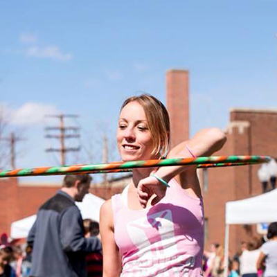 Photo of Amber Waldburger, young white woman hula-hooping outdoors.
