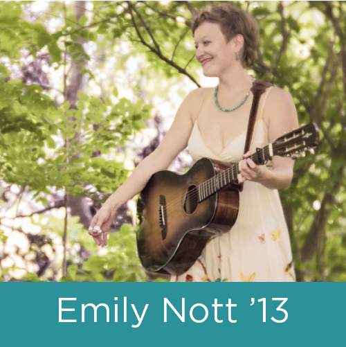 A young white woman with short blonde hair wearing a spring dress holding a guitar outside.