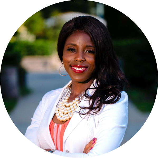 Image shows a Black woman in a white blazer with long dark hair swept to one side, smiling at the camera.