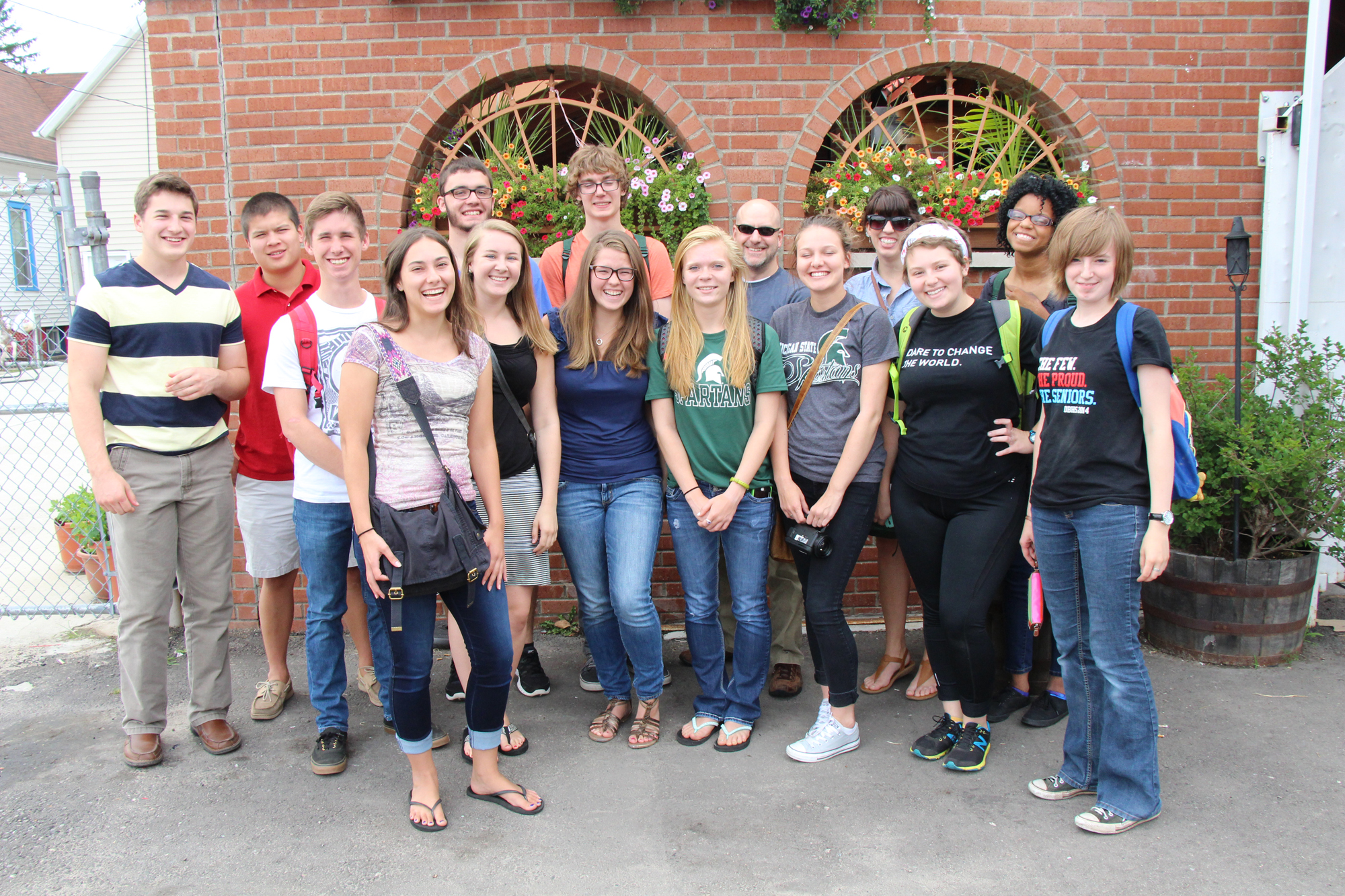 A group of diverse students stand for a photo in front of a brick building in Detroit.