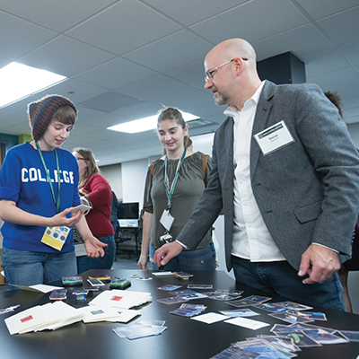 A professor, David Sheridan, stands and speaks with students in the LMC