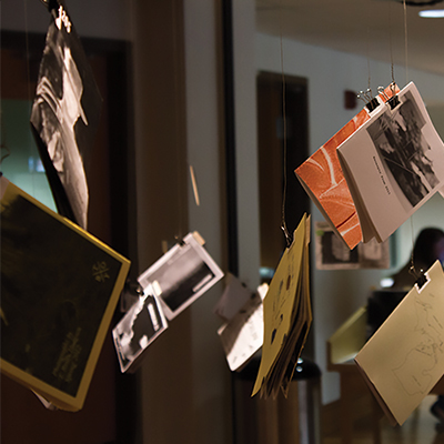 Zines hang from the ceiling on strings as part of an exhibit.