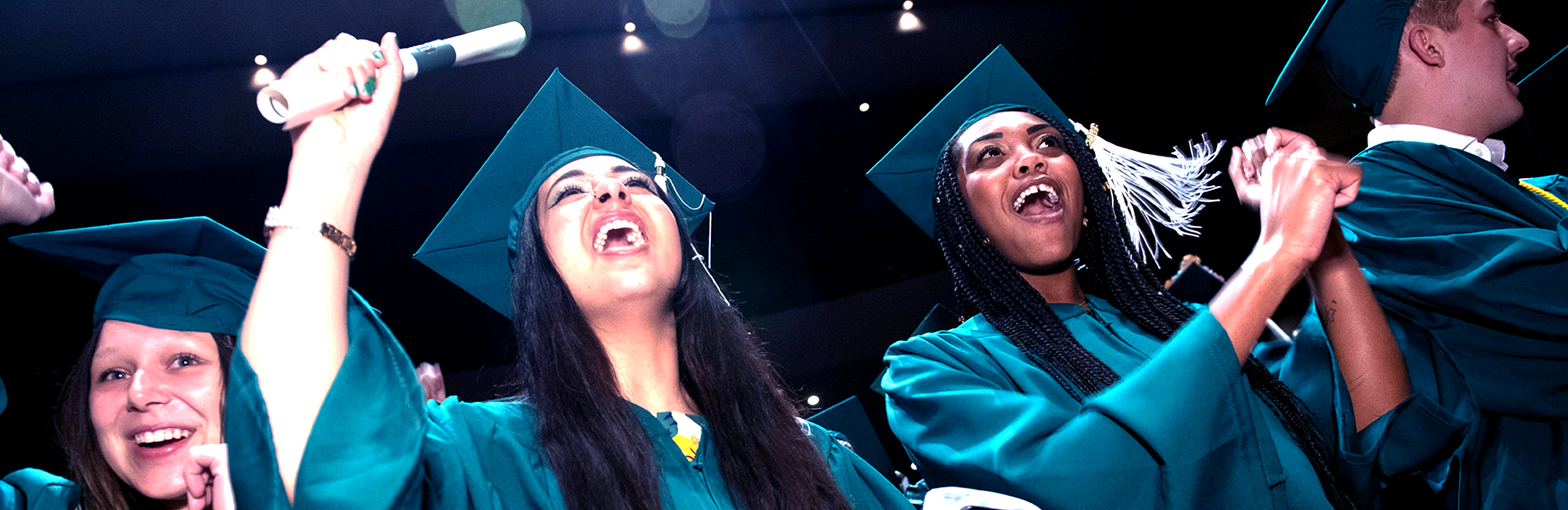 Students in commencement regalia celebrate.