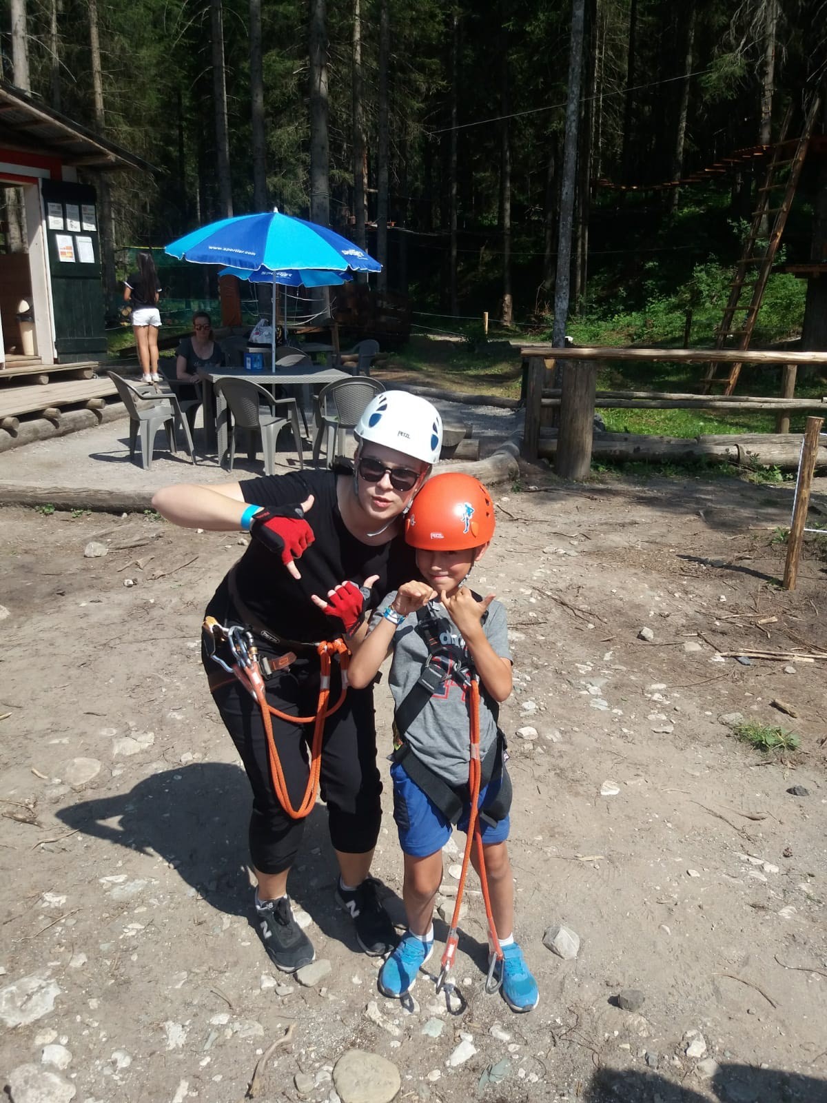 The author, a young woman, poses with a young boy while both wear climbing gear.